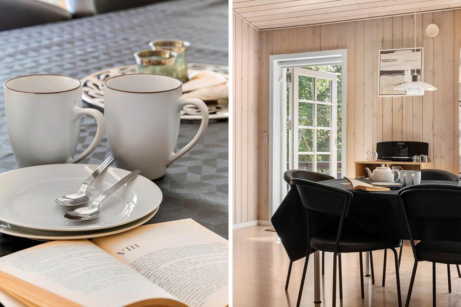Tisch mit Tassen, Tellern und offenem Buch. Esszimmer mit Tisch, Stühlen und Fenster.