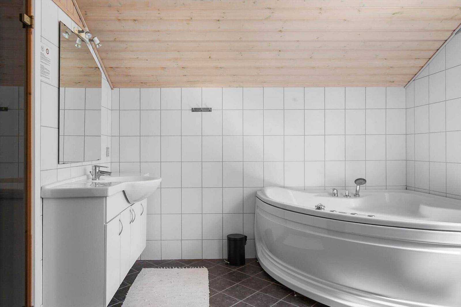 Badezimmer mit Badewanne, Waschbecken und Spiegel an der Wand.