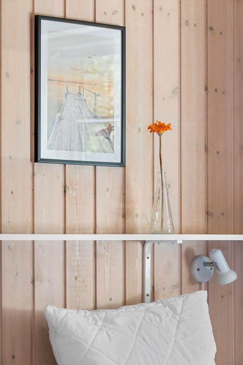 Wand mit Holzverkleidung, Bild und Vase mit Blume über Kissen