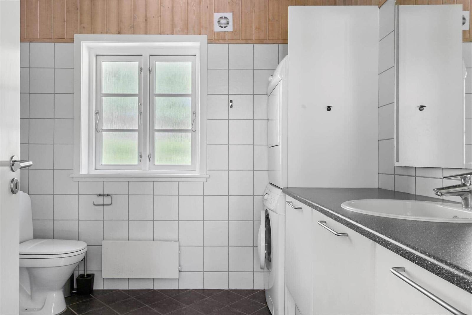 Badezimmer mit Toilette, Waschmaschine und Waschbecken.