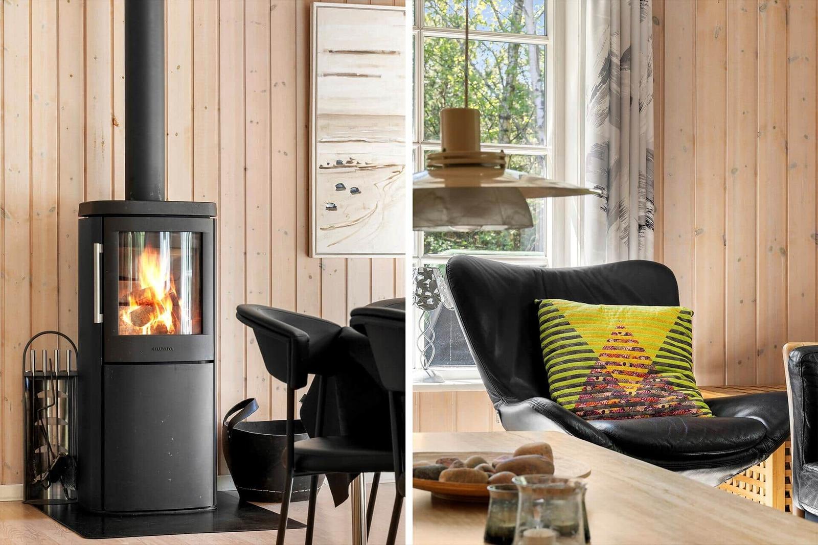 Kaminofen mit brennendem Holz, schwarze Sitzgelegenheiten und Holzwand im Wohnbereich.