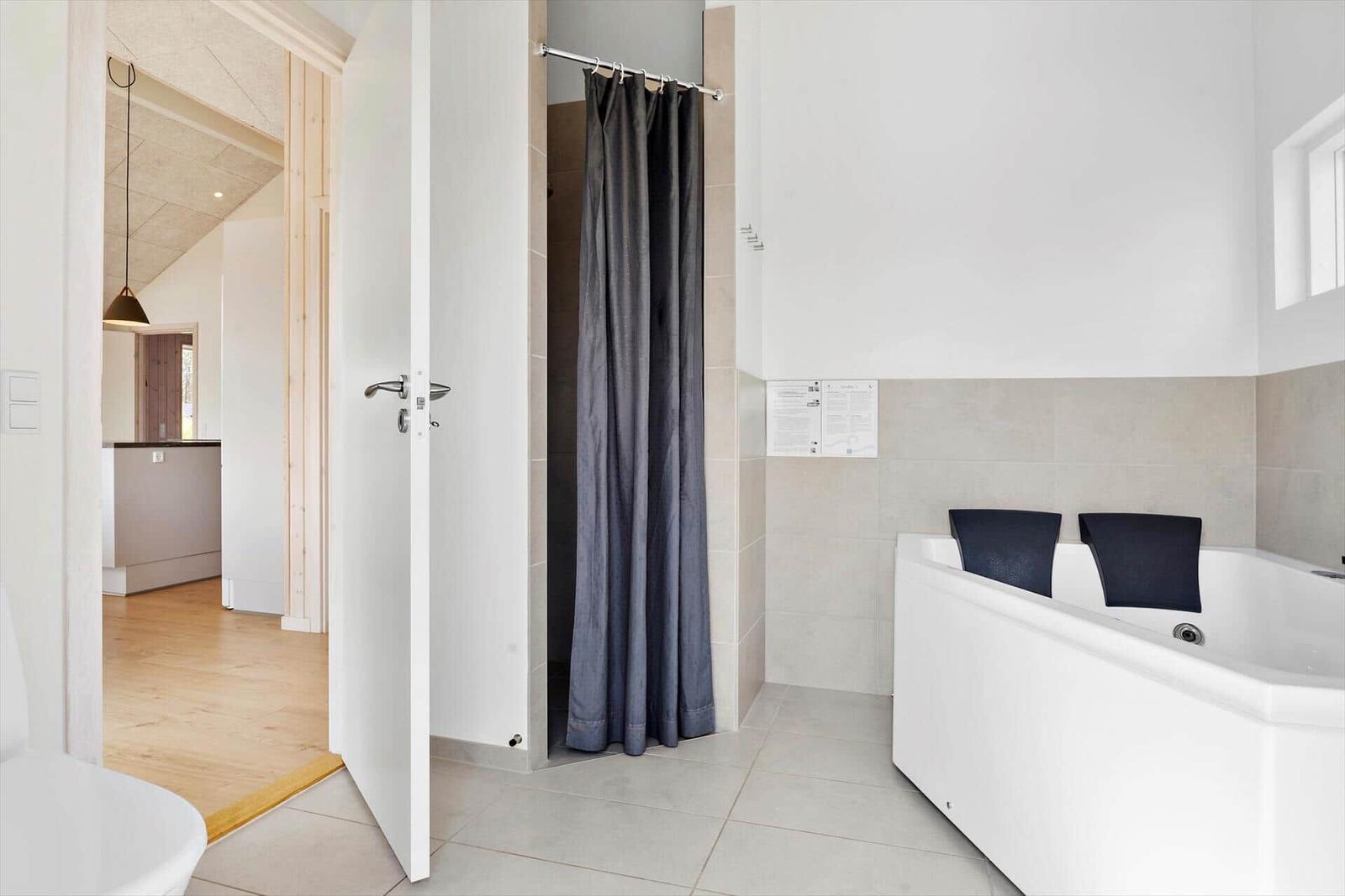 Bad mit Dusche und Whirlpoolbad. Durchgang zu Wohnbereich mit Holzboden.