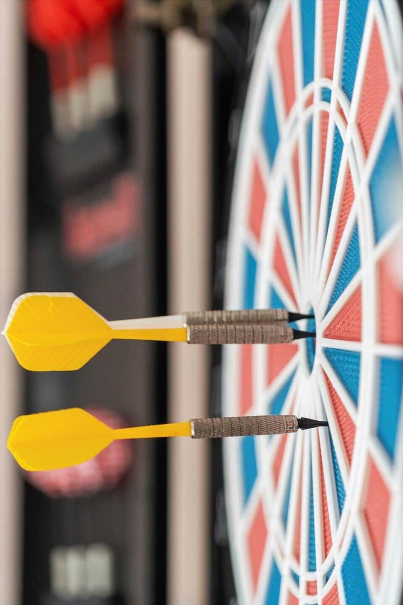 Zwei gelbe Dartpfeile stecken in einem farbigen Dartboard.