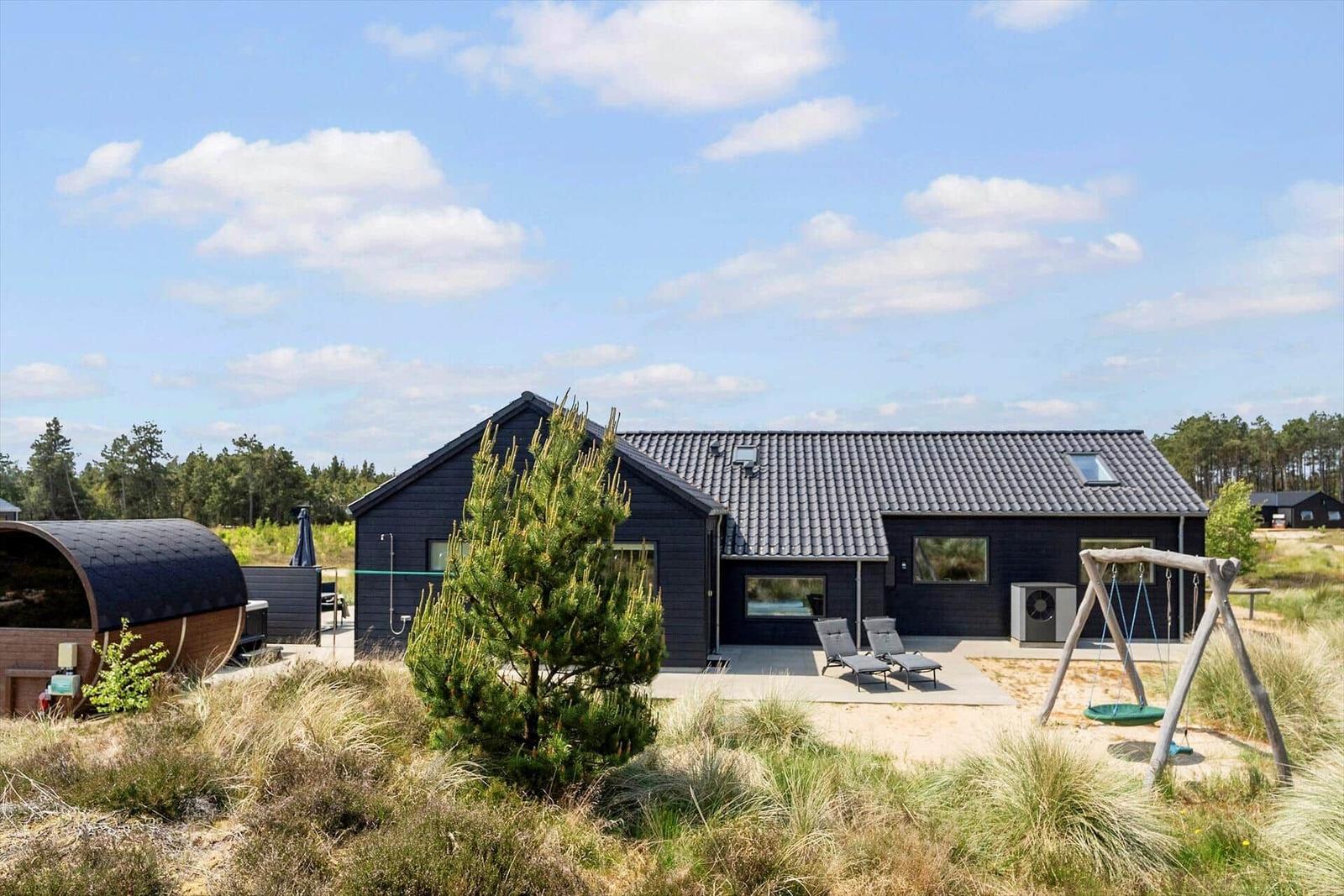 Moderne Villa mit Terrasse, Liegen und Schaukel im Freien.