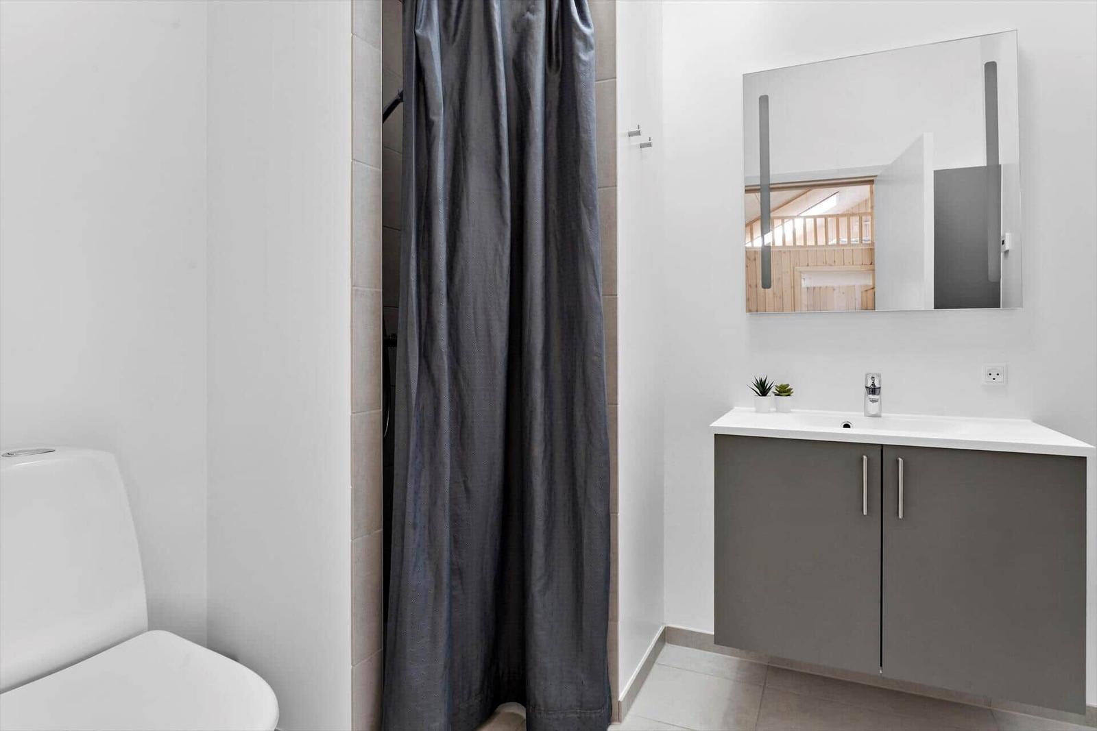 Badezimmer mit Dusche, Waschbecken und Spiegel