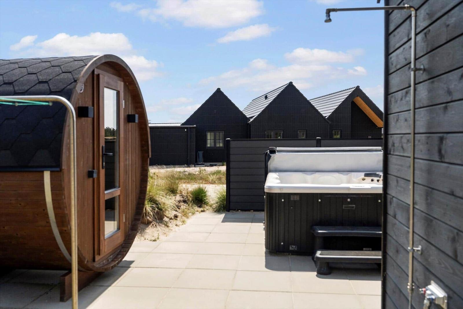 Außenbereich mit Sauna, Whirlpool und modernen Holzhäusern.