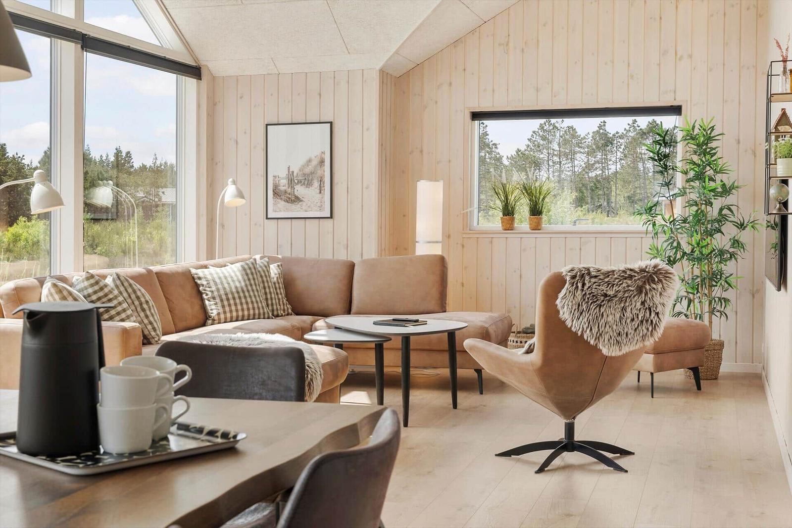 Wohnzimmer mit Sofa, Sessel und Blick auf Wald