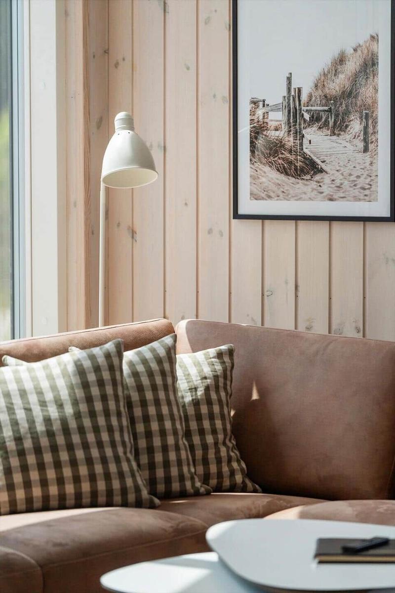Ein Sofa mit Kissen, eine Stehlampe und ein Bild an der Wand.