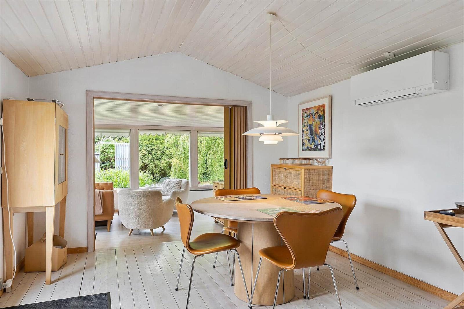 Dining room with round table and brown chairs, view to living area with seating.
