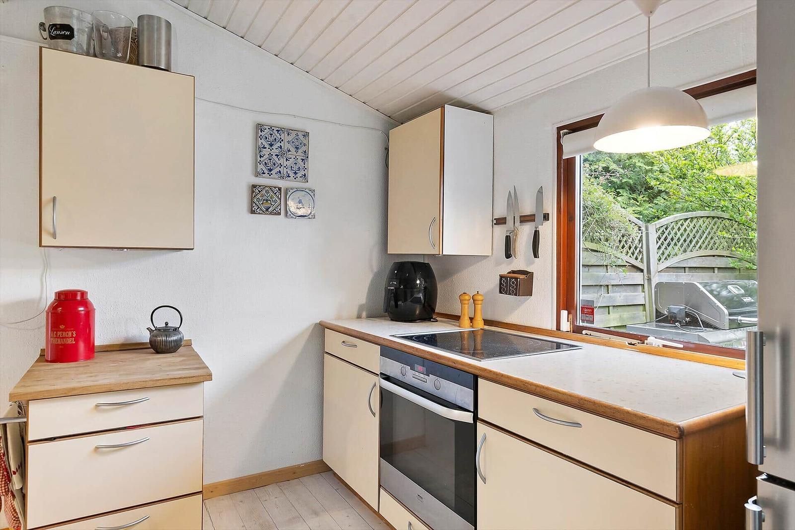 Kitchen with cabinets, stove, and window to the garden