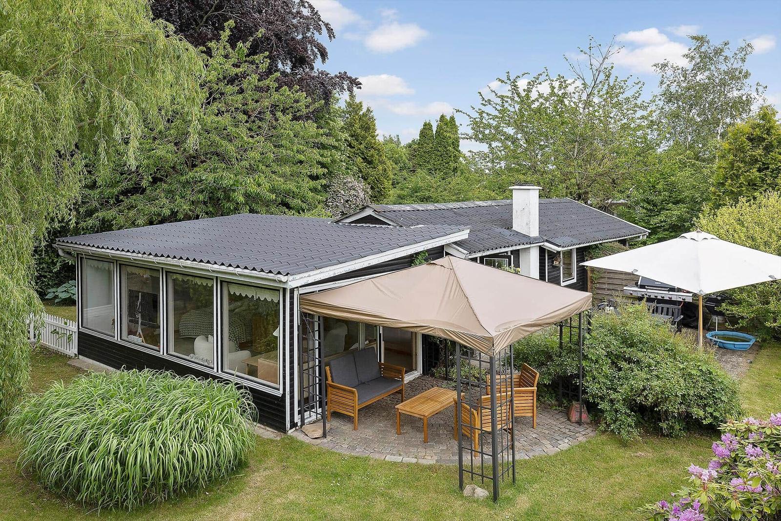 Modern villa with terrace, garden, and view of trees.