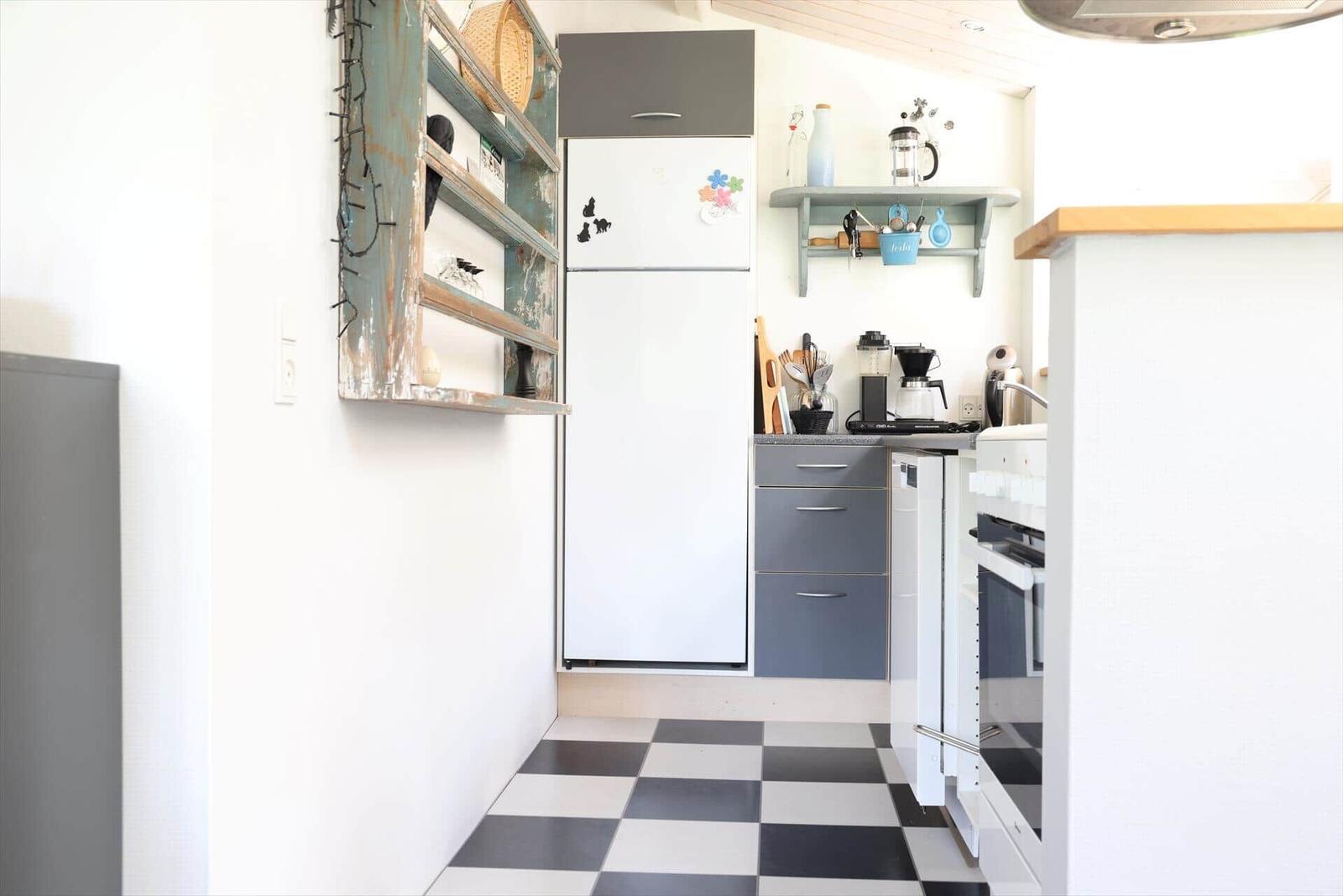 Kitchen with refrigerator, countertop, and black-and-white floor.