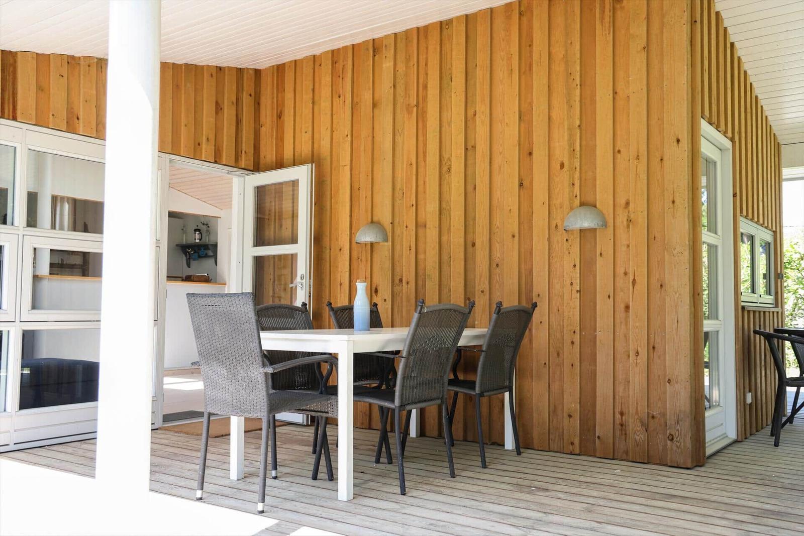 Deck with table and chairs, wooden wall and windows
