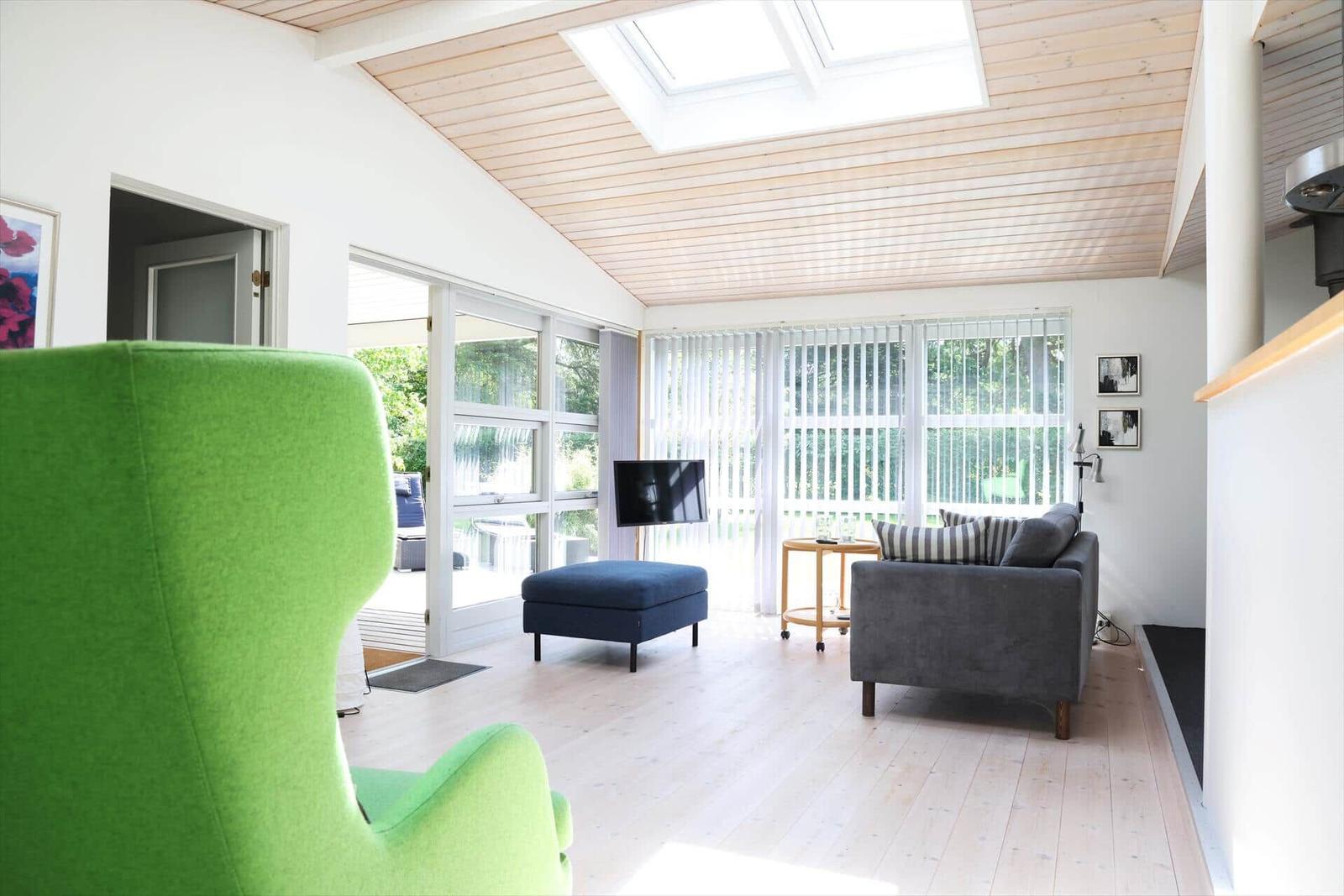 Living room with green armchair, sofa, and windows to the garden