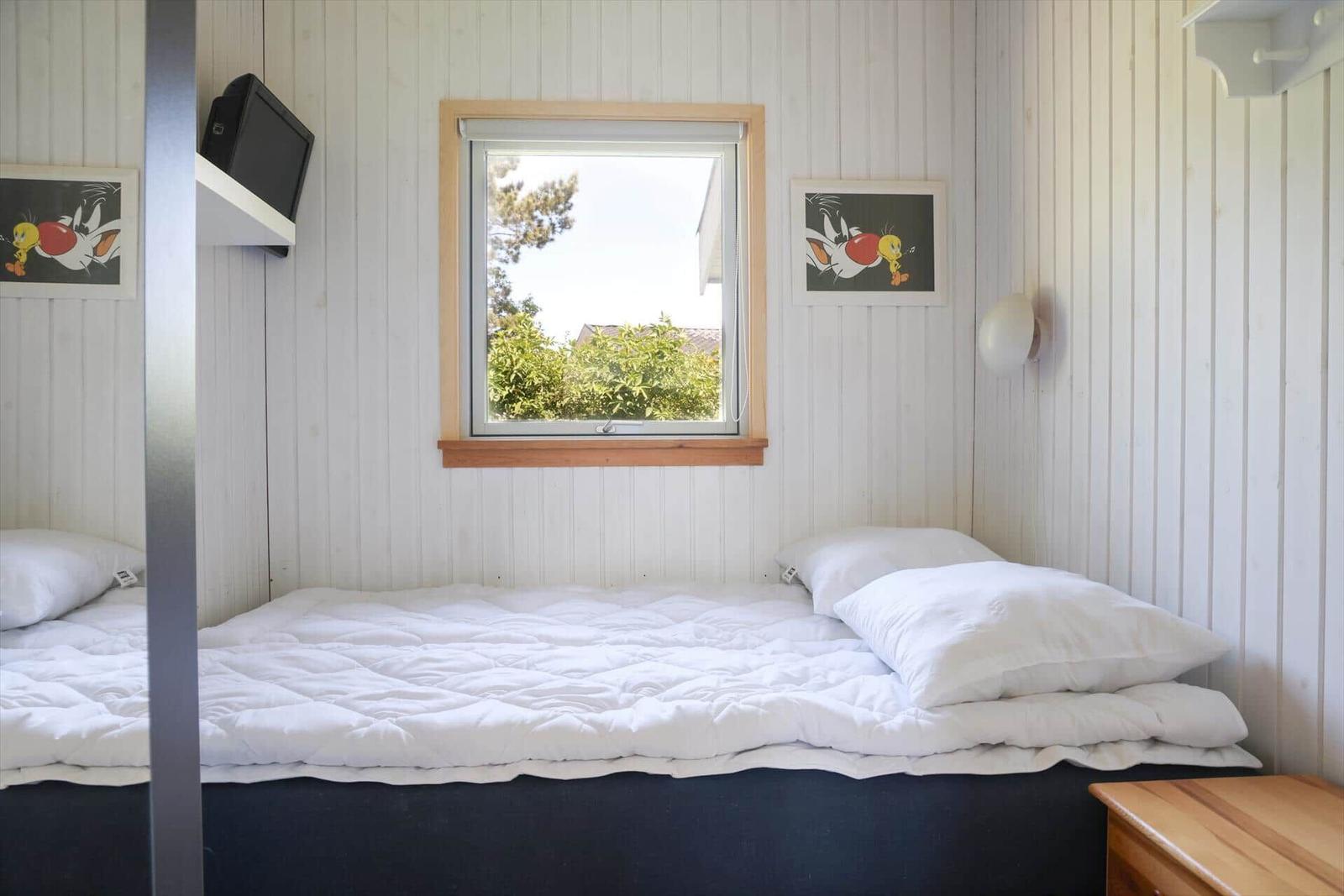 Bedroom with bed, window, and wall pictures.