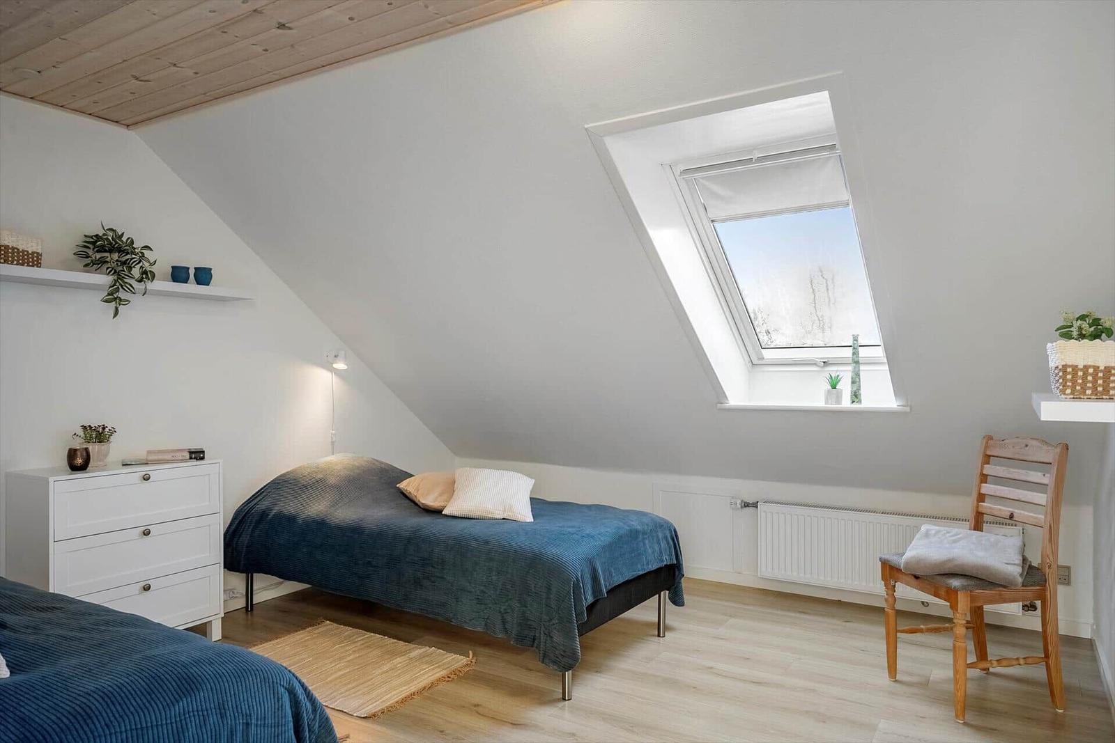 Room with sloped ceiling, bed, dresser, and window