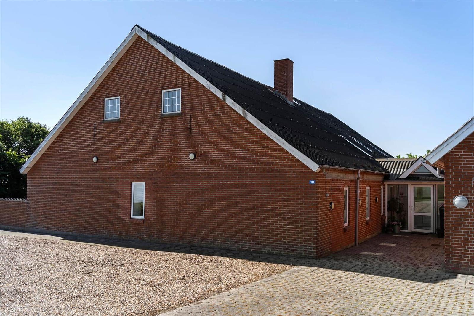 Red brick house with black roof and entrance area.