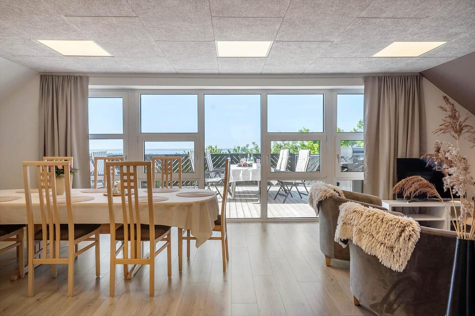 Dining room with view of balcony and sea. Furniture and fittings are visible.