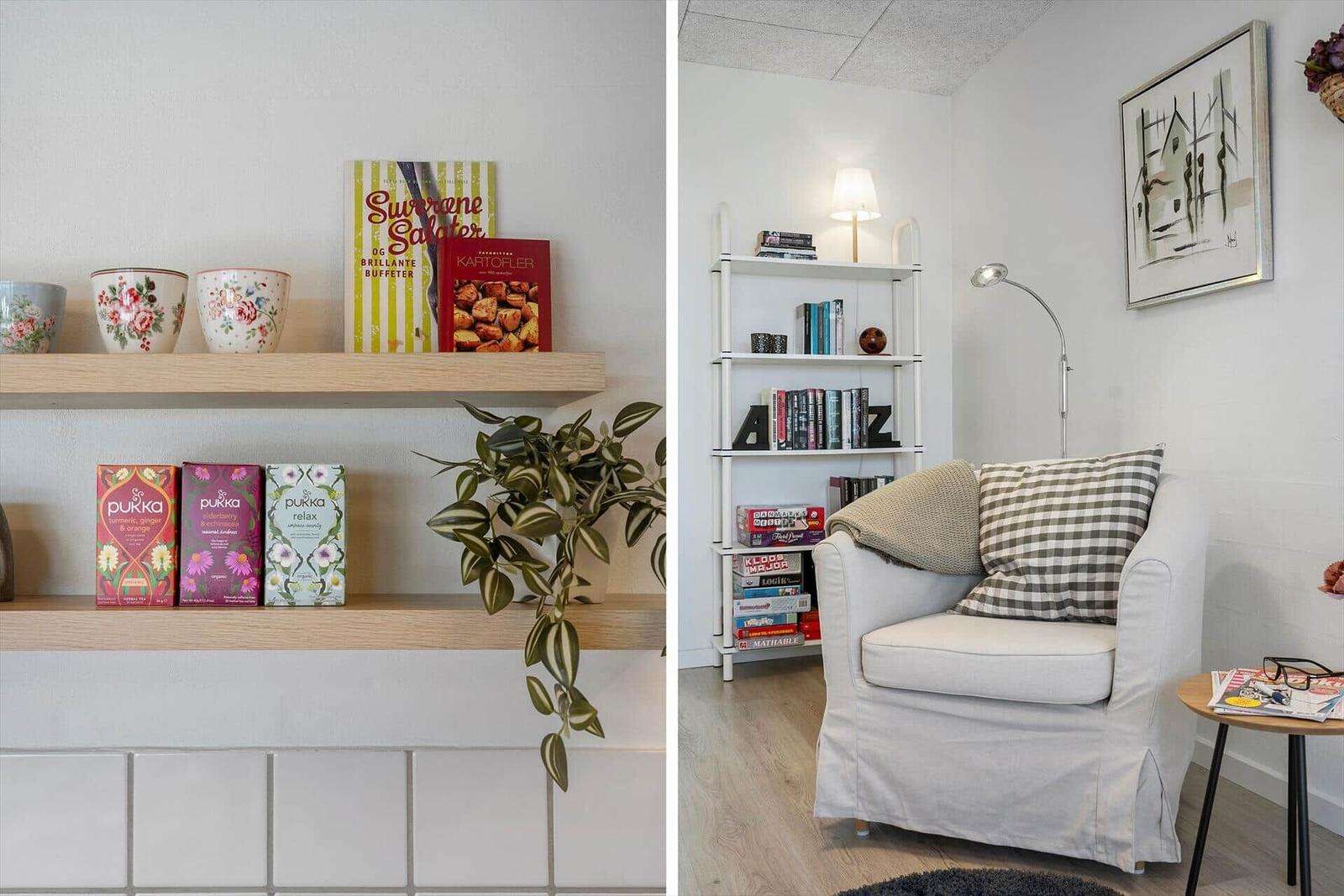 Shelf with mugs, books, and tea boxes. Seating with cushions and side table.