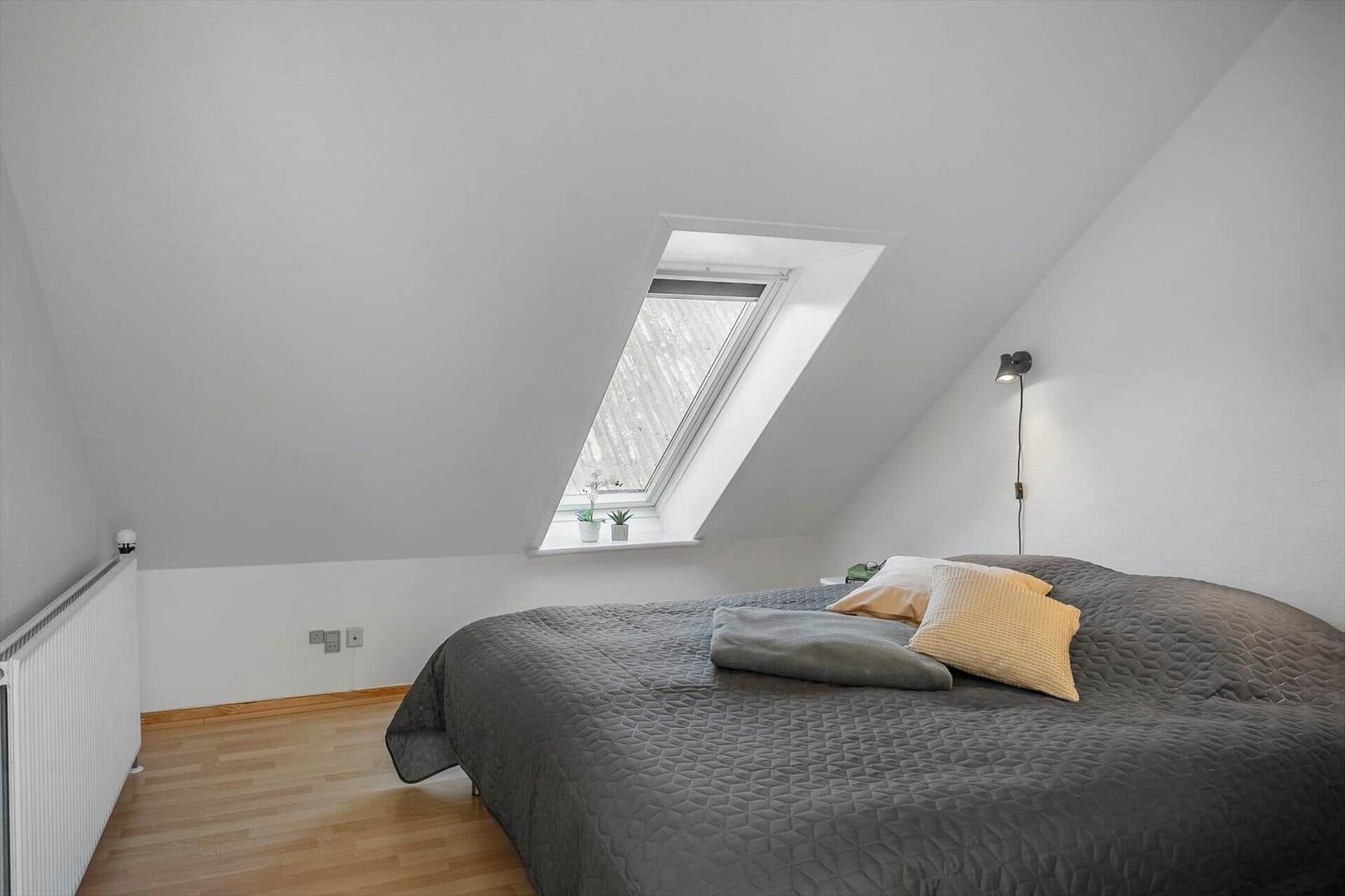 Bedroom with sloped ceiling, skylight, and wooden floor.