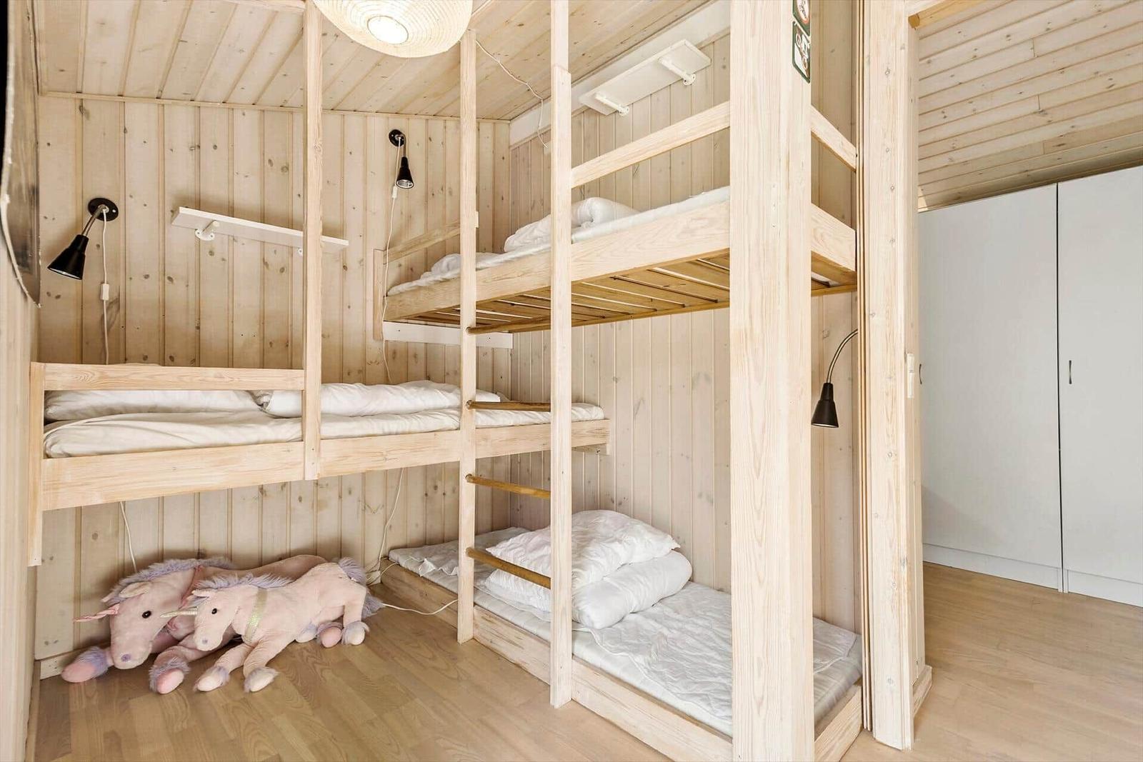 Zimmer mit Holzbetten und Kissen. Spielzeugpferde liegen auf dem Boden.