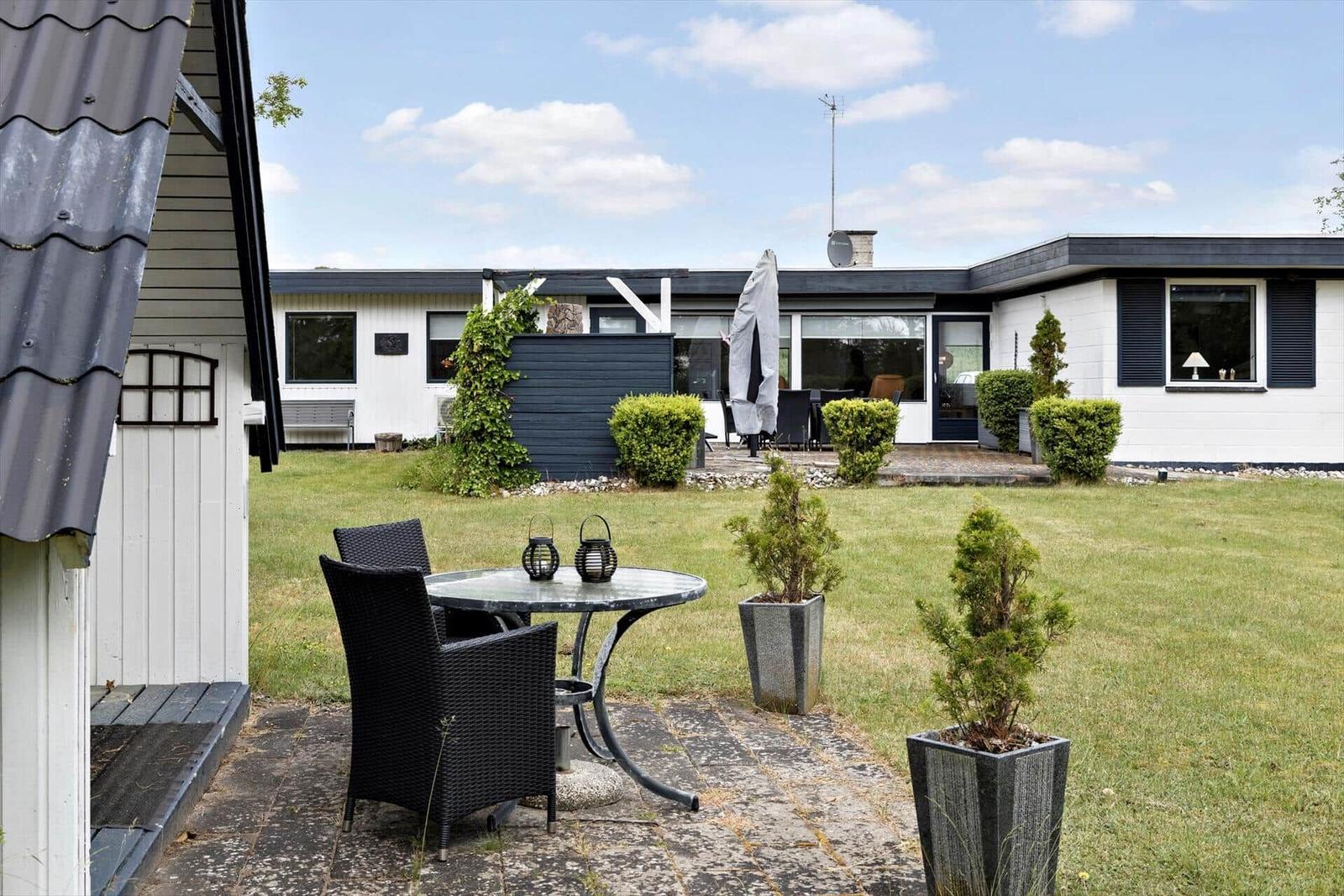 House with garden, terrace, and seating. Lawns and plants.