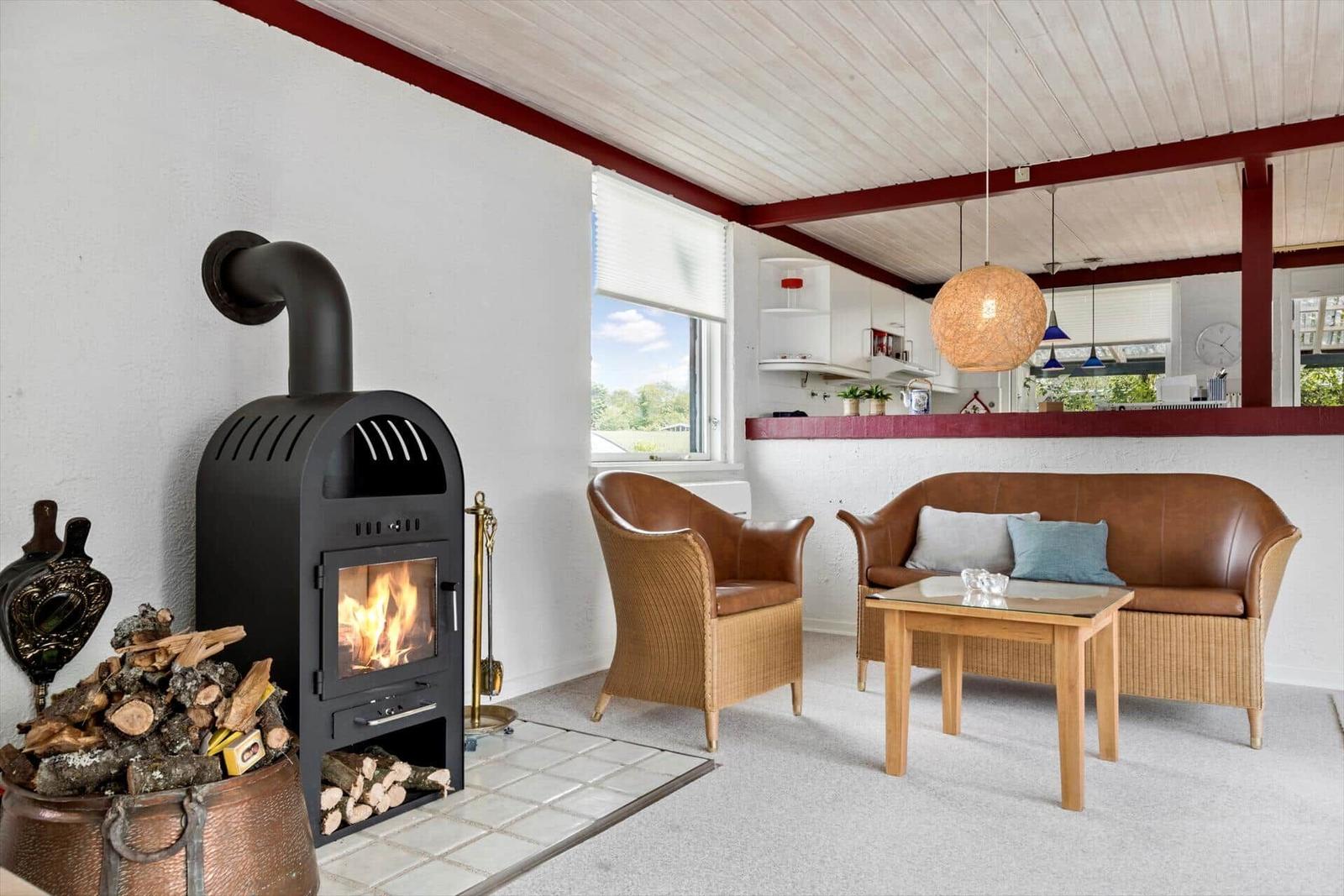 Living room with wood stove, leather sofa, and seating. Kitchen in background.