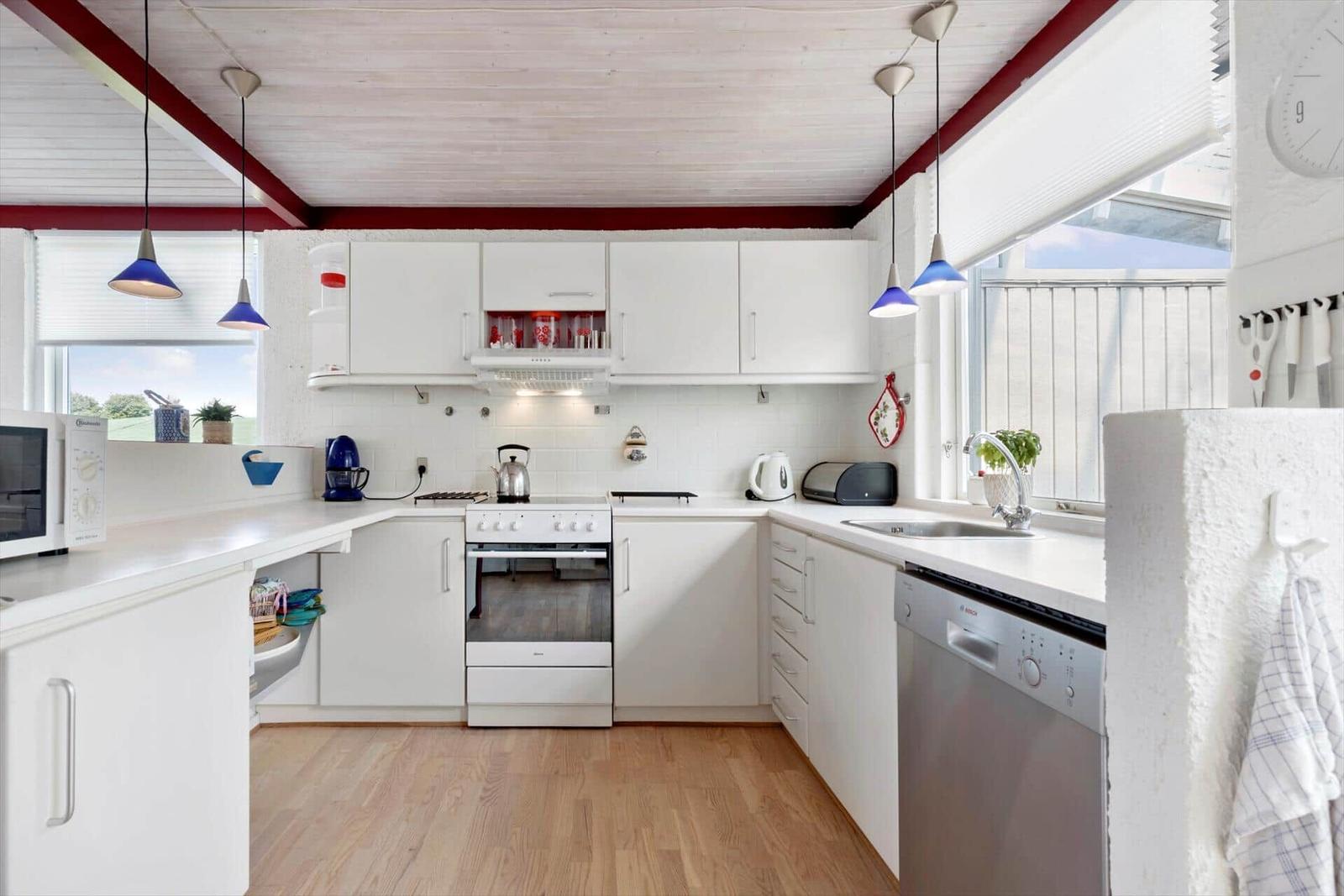 Kitchen with white cabinets, stainless steel sink, and wooden floor.