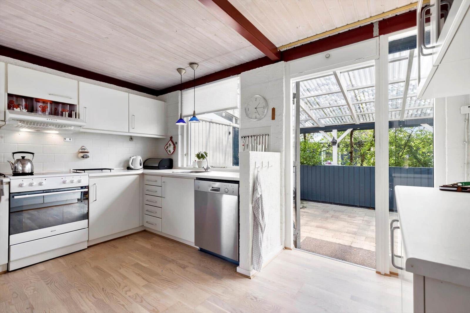 Kitchen with white cabinets, stainless steel appliances, and view of terrace.