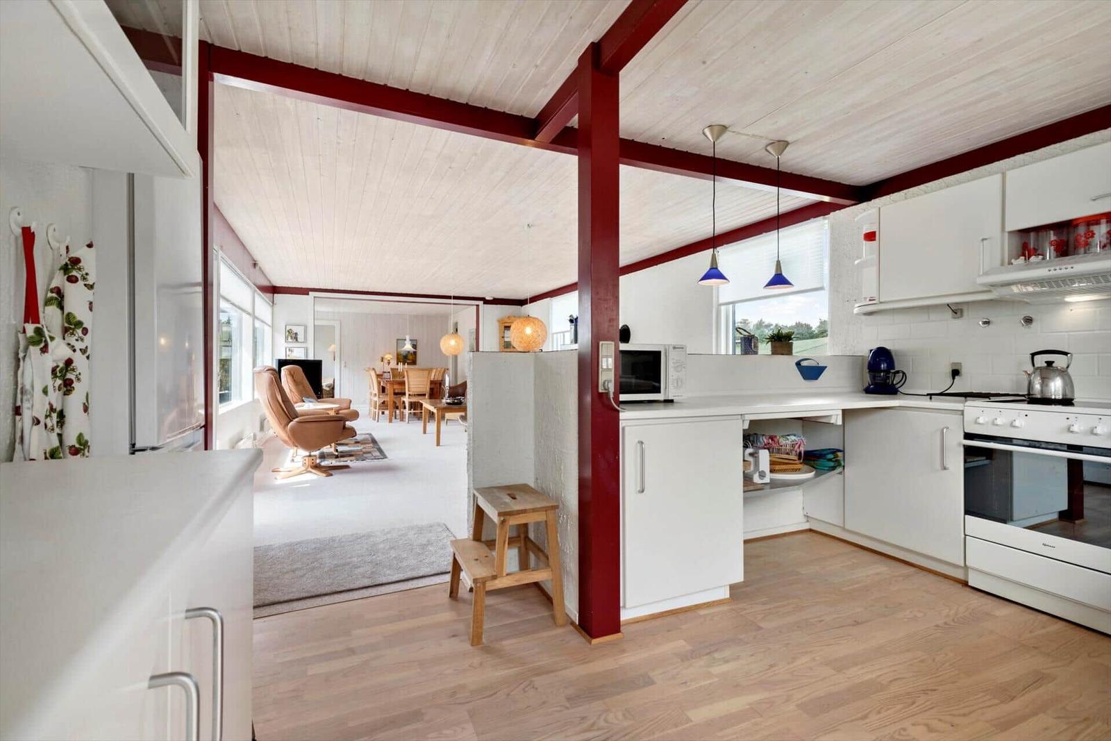 Kitchen with white cabinets and view into living and dining area.