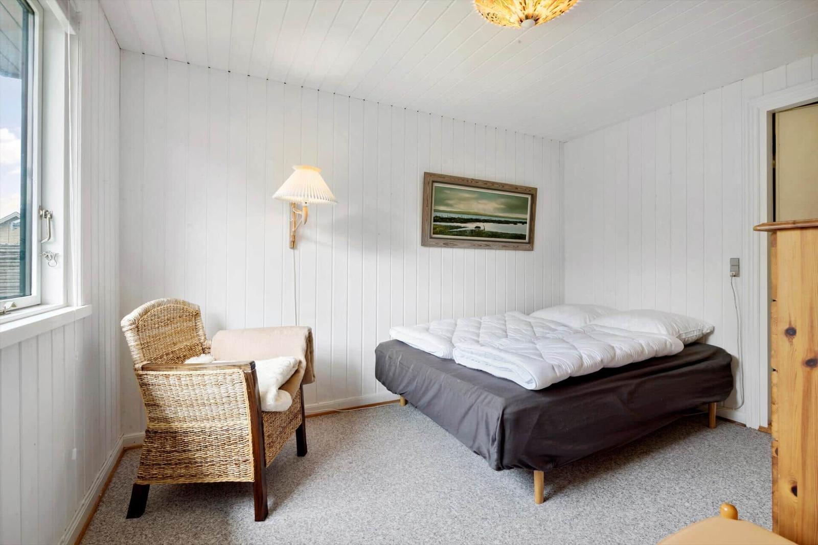 Bedroom with bed, chair, and wall picture.