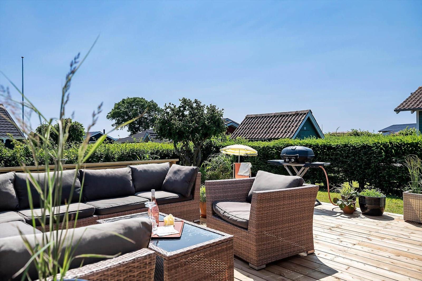 Terrasse mit Sitzgruppe, Grill und Gartenblick.