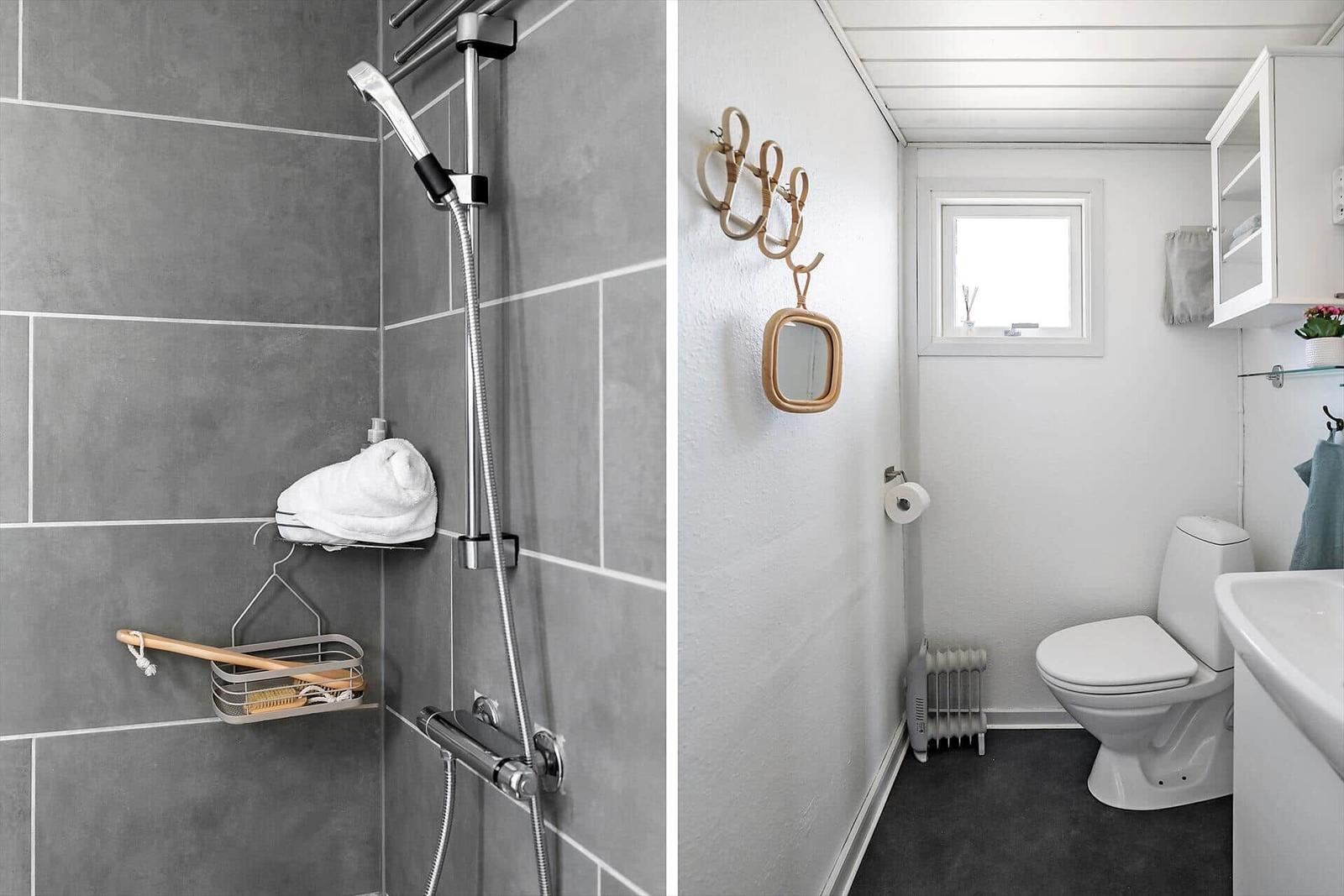 Bad mit Dusche, Toilette und Waschbecken. Weiße Wände und graue Fliesen.
