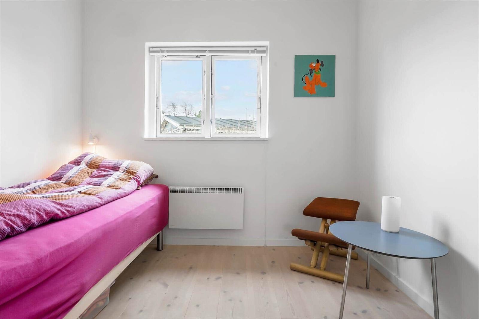 Ein Zimmer mit Bett, Fenster, Tisch und Stuhl.