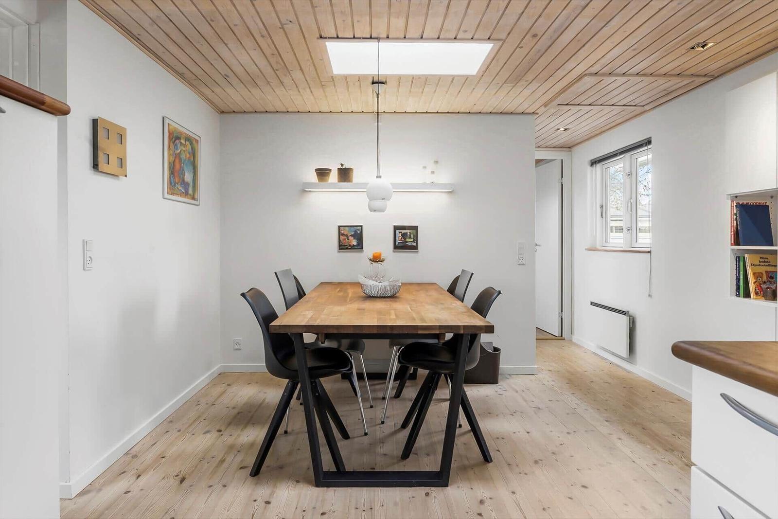 Esszimmer mit Holzboden, Tisch und Stühlen, Deckenlicht und Fenster.