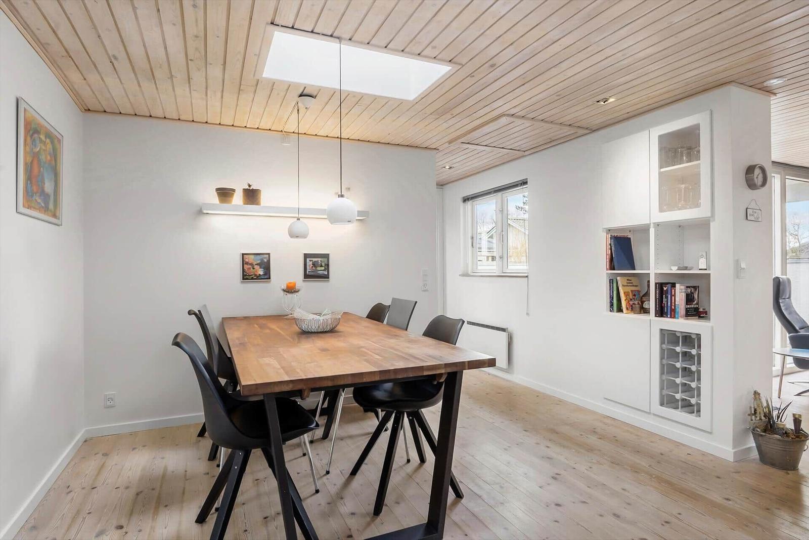 Esszimmer mit Holztisch, schwarzen Stühlen und weißen Schränken an der Wand.