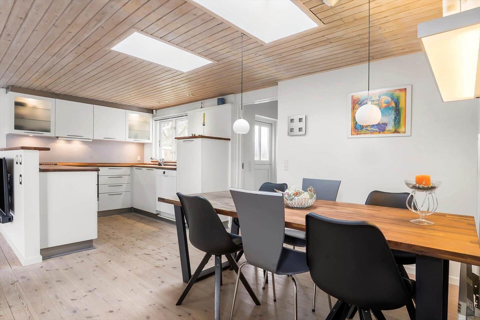 Küche und Essbereich mit Holzboden, weißen Schränken und Holztisch mit Stühlen.