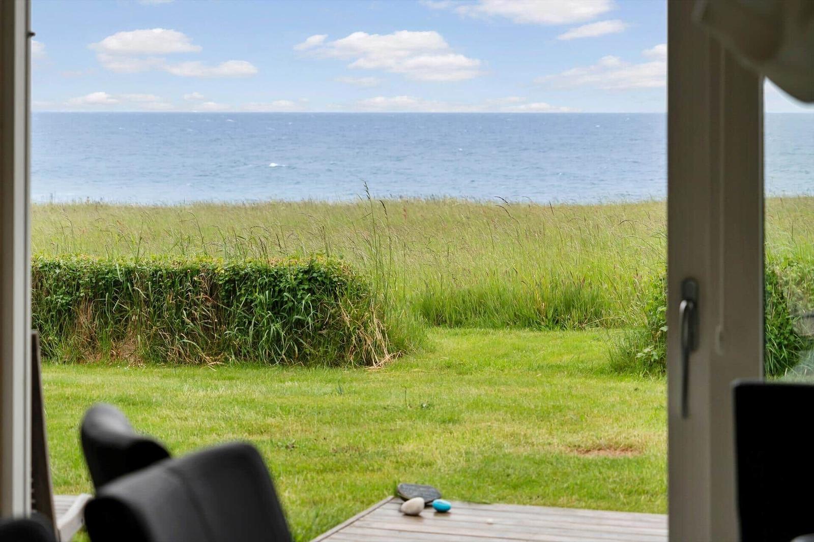 Von der Terrasse aus bietet sich ein Blick auf das Meer und grünes Gras.