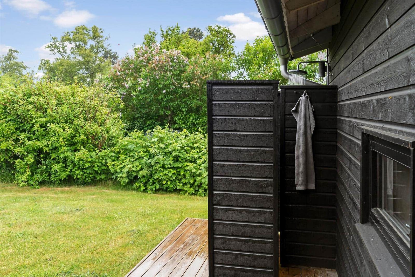 Außen-Dusche neben Haus mit Grünfläche und Bäumen