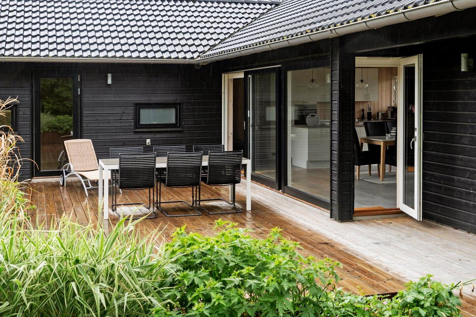 Terrasse mit Tisch, Stühlen und Blick in die Küche.