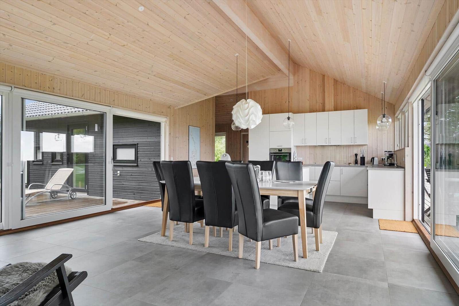 Eingangsbereich mit Essbereich und Küche. Holzdecke und große Fenster.