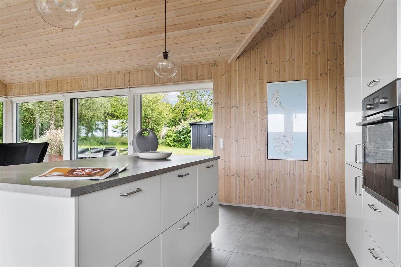 Moderne Küche mit Holzwand und großem Fenster. Arbeitsplatz mit Kücheninsel.