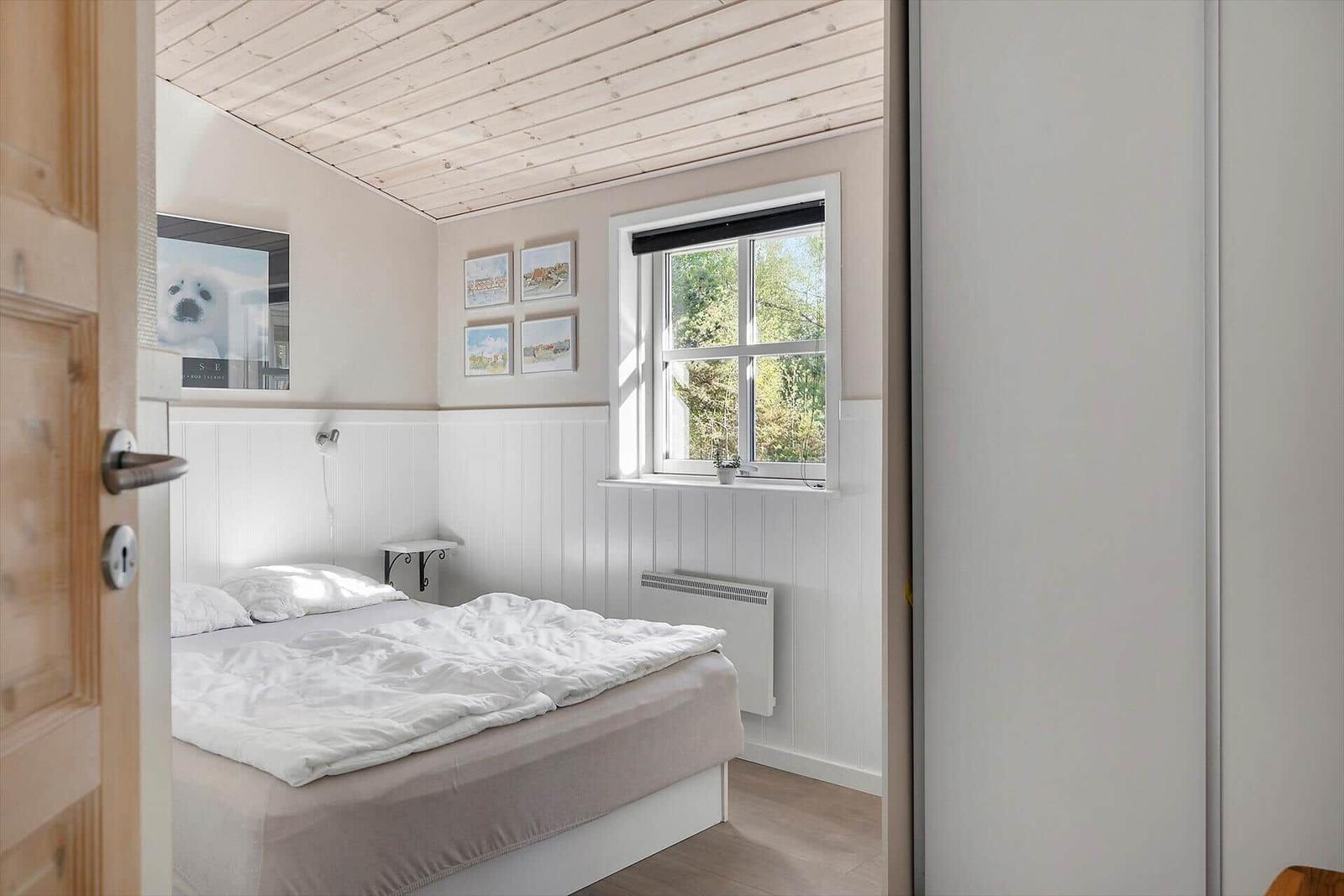 Schlafzimmer mit Bett, Fenster und Wanddekoration.