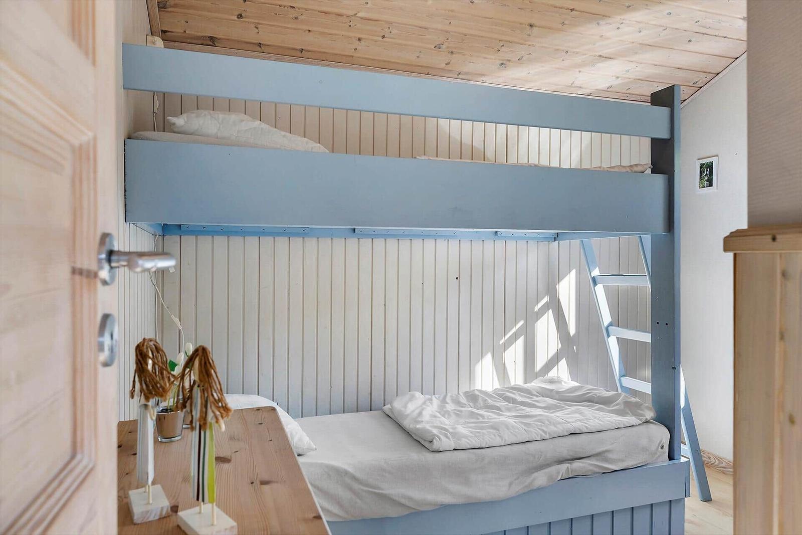 Ein Schlafzimmer mit einem blauen Doppelstockbett und einem Holztisch.