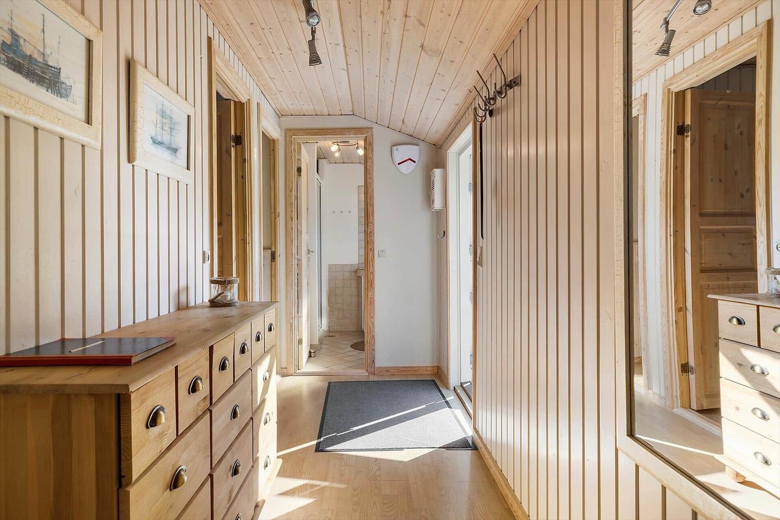 Flur mit Holzwandverkleidung, Schuhschrank und Blick in Bad und Schlafzimmer.