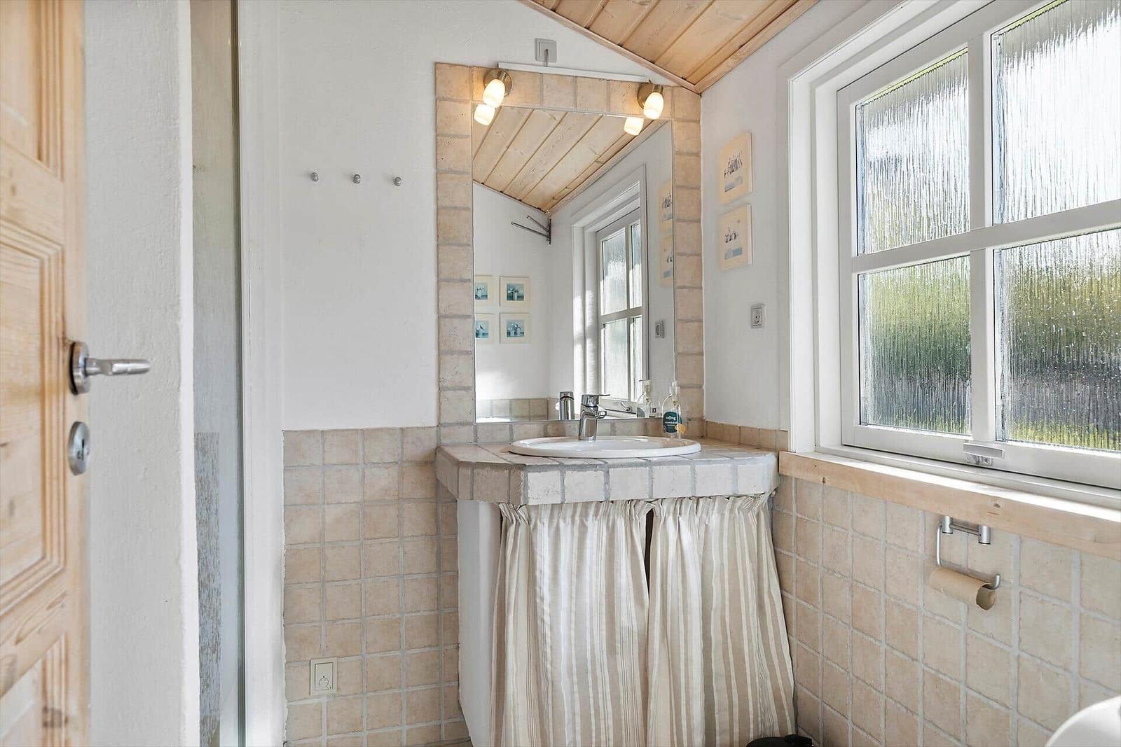 Badezimmer mit Waschbecken, Spiegel und Fenster