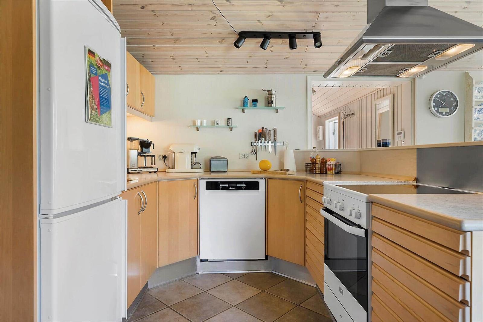 Küche mit Holzschrank, Spüle, Kühlschrank und Kochfeld.