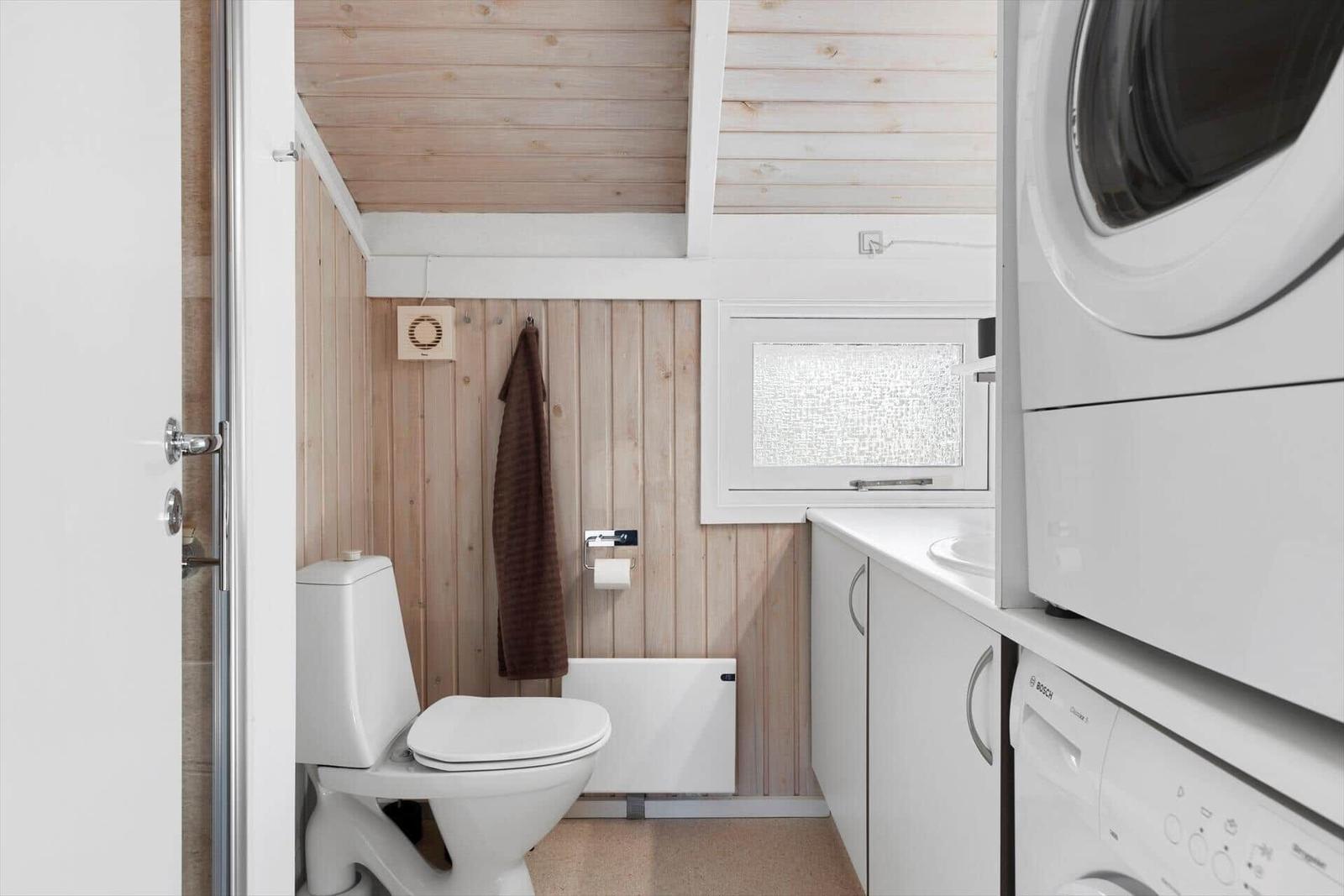 Bathroom with toilet, washing machine, and window.