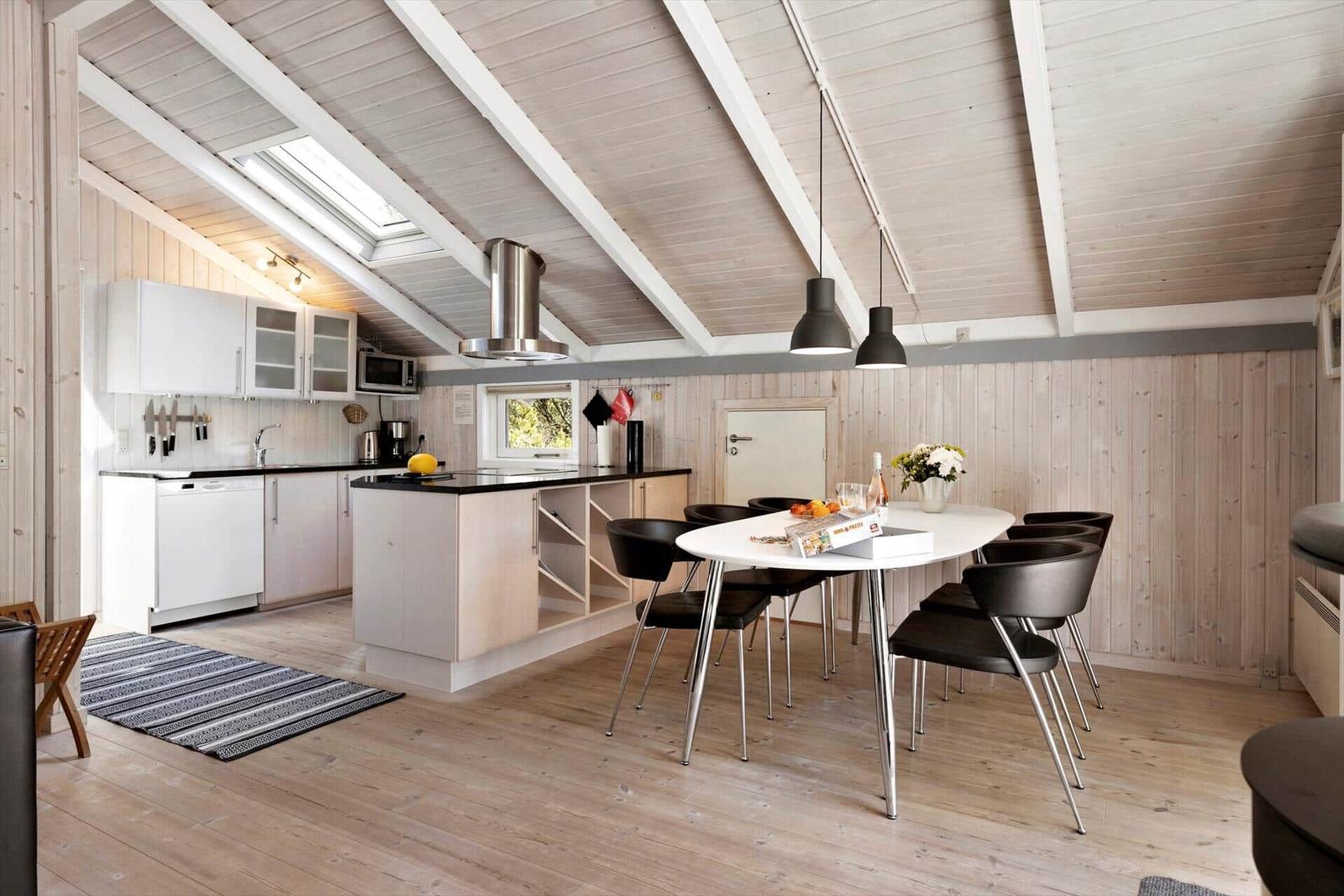 Kitchen with dining area under wooden roof with skylight.