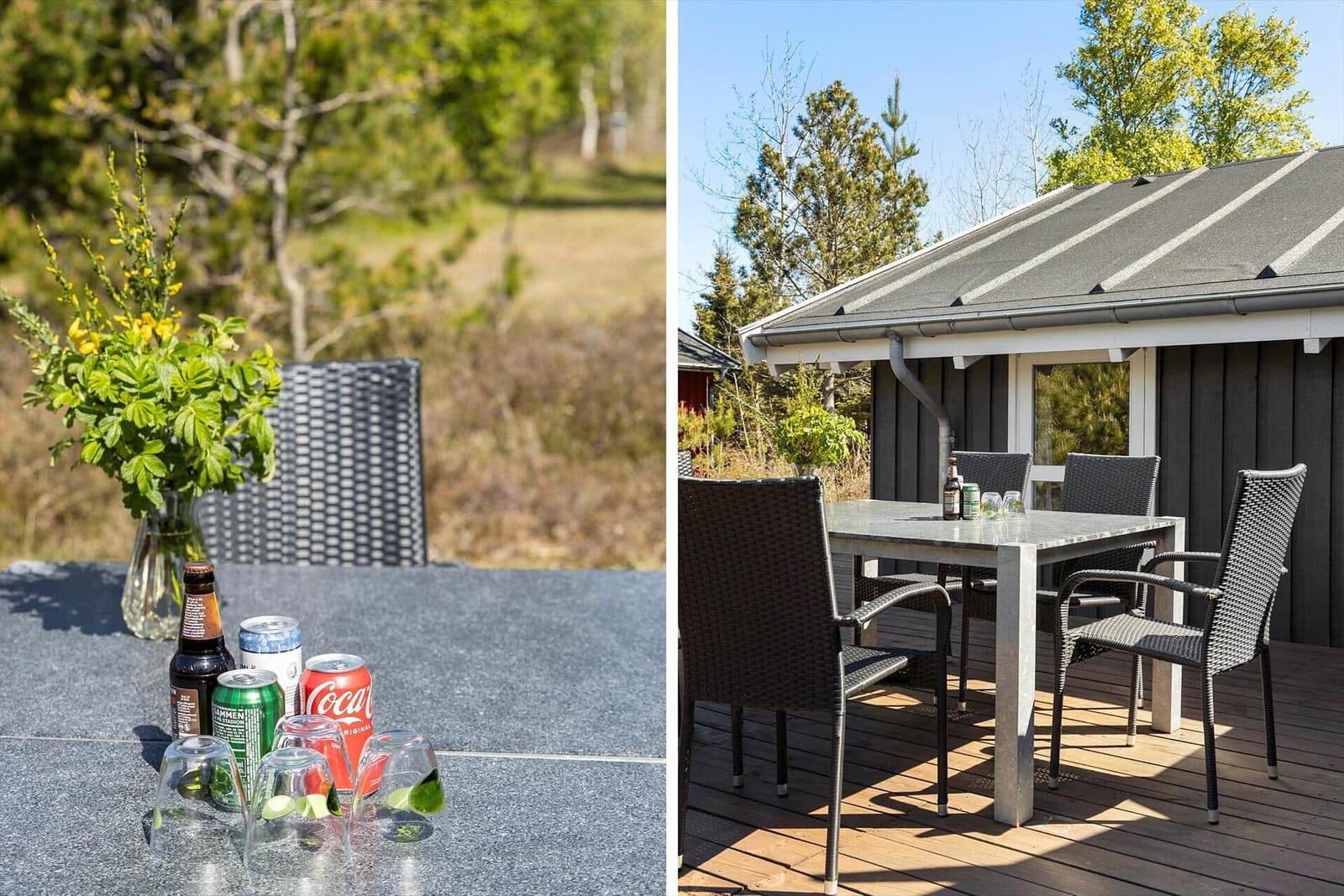 Deck with table and chairs, flowers and drinks. Background: forest and house.